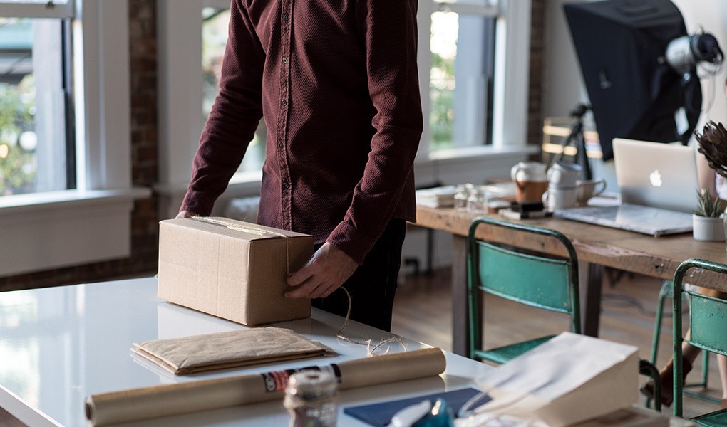 A person is applying tape to a cardboard box.